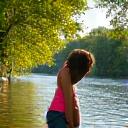 A person enjoying an active walk or hike along a scenic river trail, illustrating physical activity in a natural setting