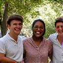 Three diverse individuals cheerfully interacting in a park setting, symbolizing strong social connections and community engagement